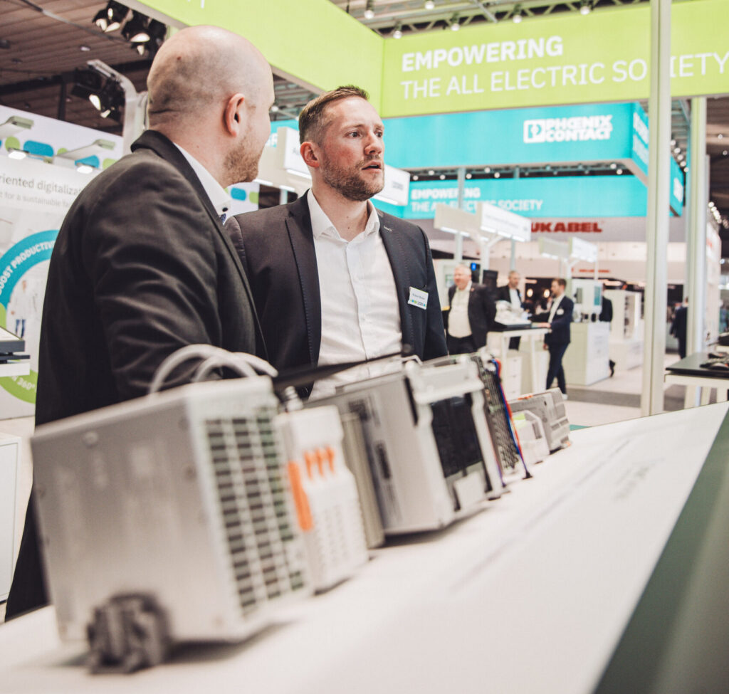 Hannover Messe 2025. Phoenix Contact Stand, Gespräch mit Hardware im Vordergrund